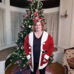 enchanted evening storyteller standing in front of a decorated christmas tree