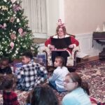 storyteller reading to the children who are gathered around her sitting on the floor