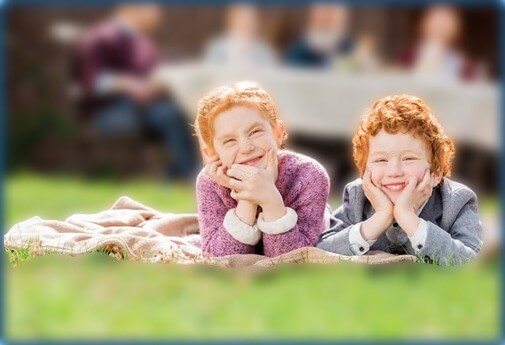 children sitting on blanket outside listening to storytelling