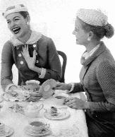 photo of two women having tea and laughing when one flips a plate over to see the back stamp