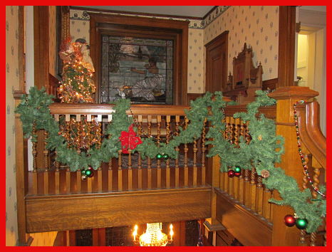 holiday decorations on upstairs staircase with stained glass window in background