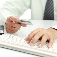 Donate Online image of hand holding credit card with computer keyboard