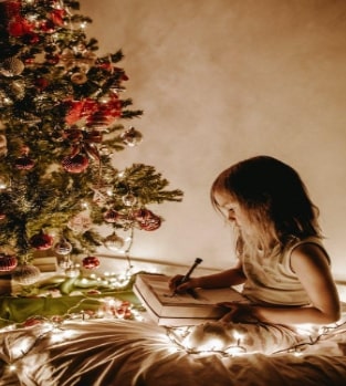 little girl sitting by decorated christmas tree