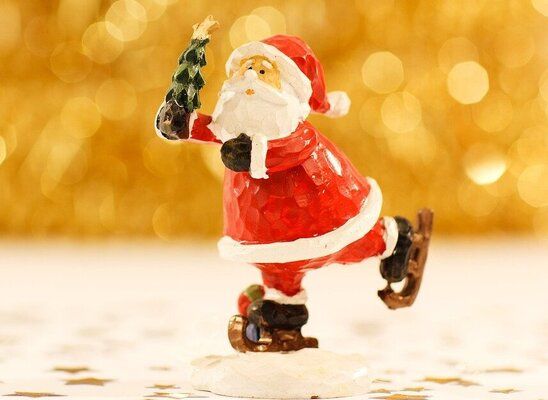 photo of santa claus ice skating while holding a miniature christmas tree